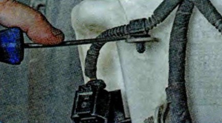 Поддев отверткой, отсоедините от бачка пластмассовый держатель жгута проводов Skoda Octavia
